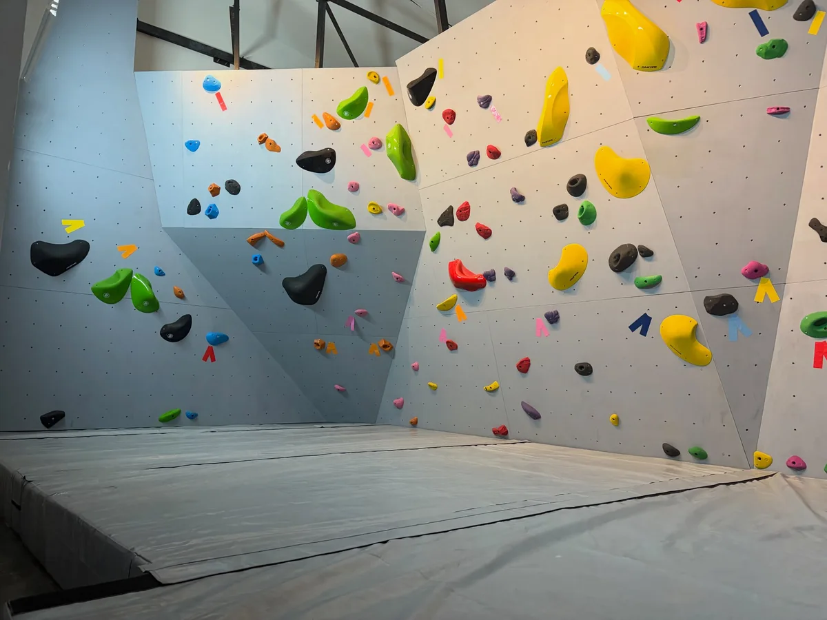 Angled bouldering walls with colourful holds and padded landing at Chill Out Climbing Gym